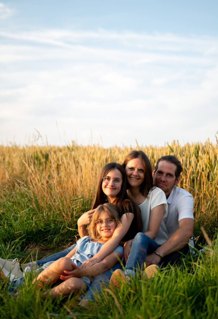 Babyfotos zuhause Eine Familie sitzt beim Fotoshooting in Herford im Feld.